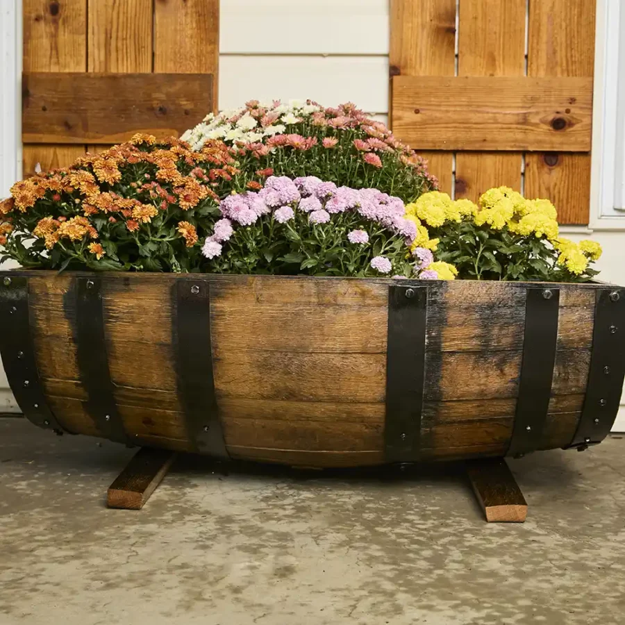 whiskey barrel planter cut lengthwise resting on staves to keep it off the ground
