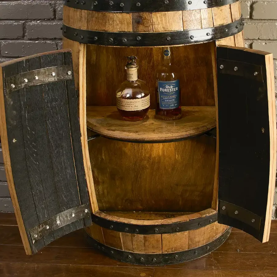 Half bourbon barrel cabinet with doors open with 2 bottles of liquor on a barrel lid shelf