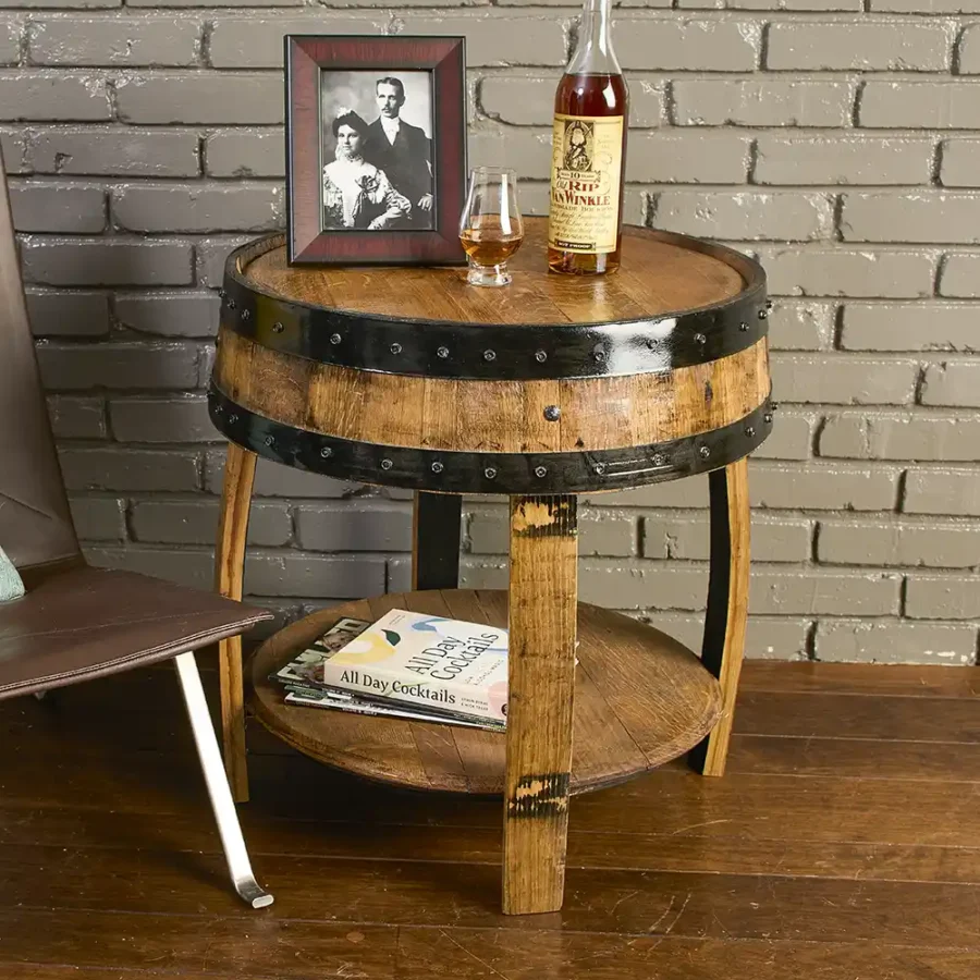 Whiskey barrel end table with shelf a few inches off the ground. Liquor bottle and Glencairn glass on the top