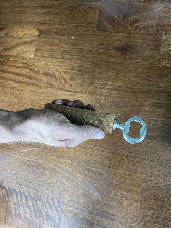 Someone holding a whiskey barrel stave bottle opener