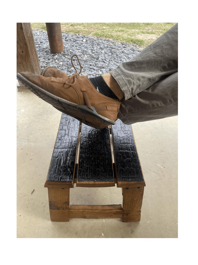 Barrel stave footrest with someone's feet resting on it